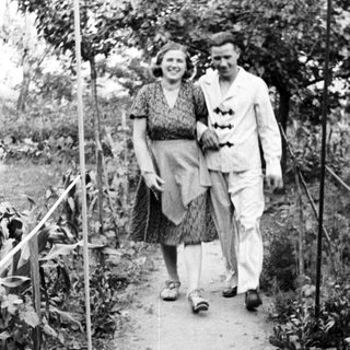 Couple walks along a path in a garden.