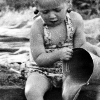 Here's a brief summary of the image: Child plays in a shallow pool outdoors.