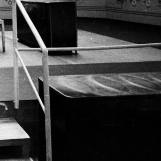 Man operating controls in a vintage control room.