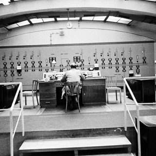Man operates control panel in a vintage monitoring room.