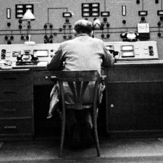 Man working at control panel in a monitoring room.