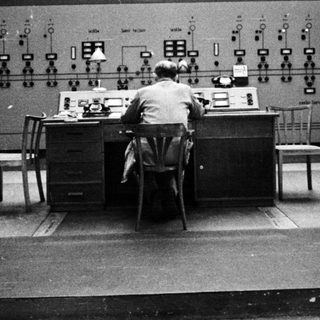 Man working at control panel in a monitoring room.