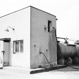 Industrial building with tank and equipment in a black and white photo.