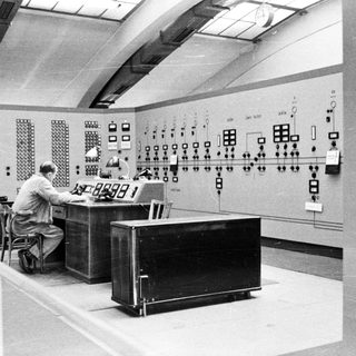 Control room with operators monitoring complex electrical systems.