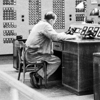 Control room with operators monitoring complex electrical systems.
