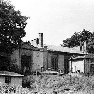 Black and white photo of an old brick building and foliage.