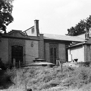 Abandoned building with unusual architecture, overgrown vegetation in foreground.