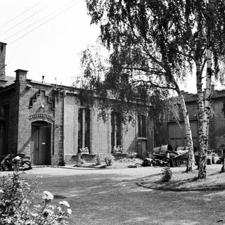 Black and white image of a building with vehicles nearby.