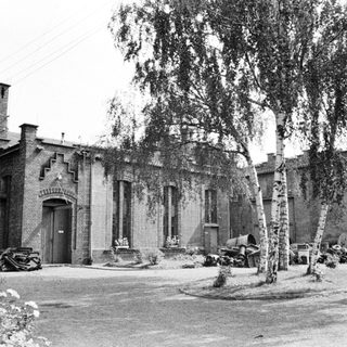 Old brick building with trees and equipment in the yard.