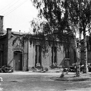 Black and white photo of a brick building with trees.