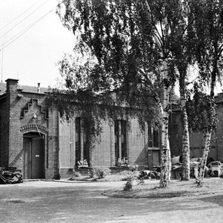 Black and white photo of a brick building with trees.