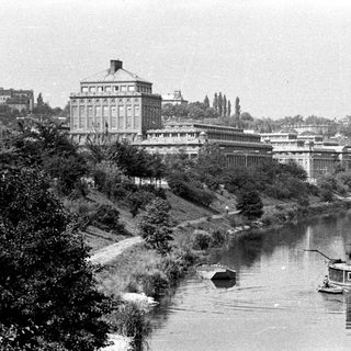 Riverfront scene with a large building and steamboat.