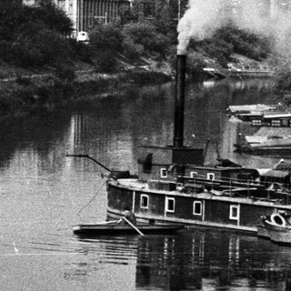 Industrial building and river with a steamboat.