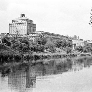 Large building reflected in a calm river landscape.