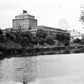 Black and white photo of a large building and river.