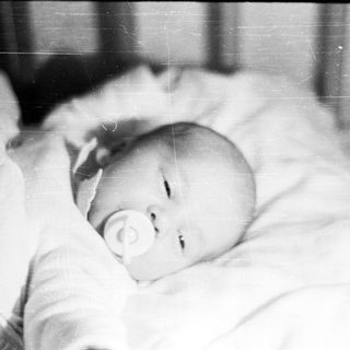 Baby lying down with a pacifier in their mouth.