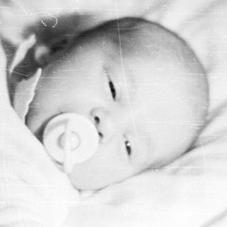 Baby lying down with a pacifier in their mouth.