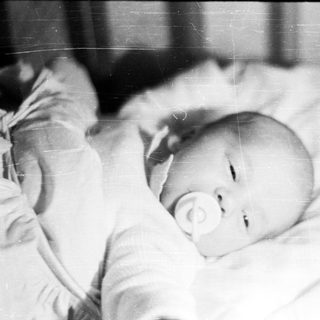 Baby lying down with a pacifier in their mouth.