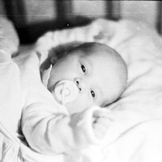 Black and white photo of a baby in a crib.