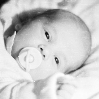 Black and white photo of a baby in a crib.