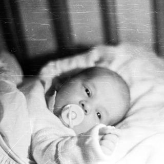 Black and white photo of a baby in a crib.