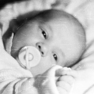 Black and white photo of a baby in a crib.