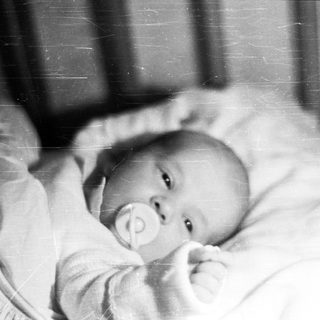 Black and white photo of a baby in a crib.