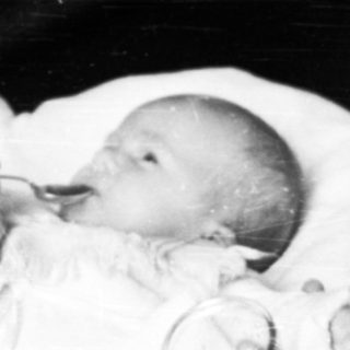 Woman feeding a baby in a hospital setting.