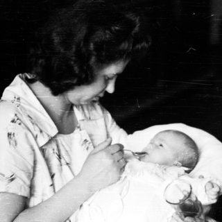 Woman feeding a baby in a hospital setting.