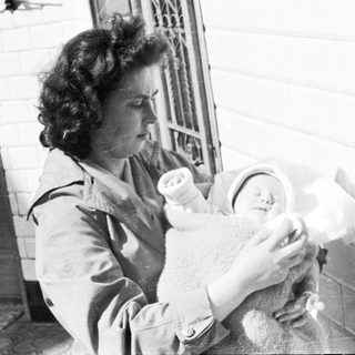 Woman holding a baby wrapped in a blanket.