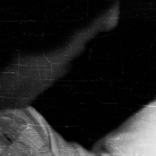 Here's a brief summary of the image: Black and white photo of a baby in a crib.