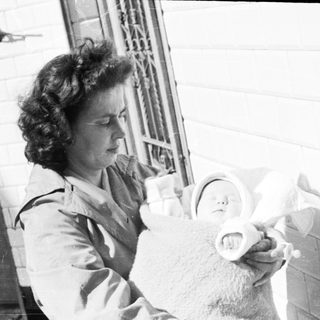 Woman holding a baby on a porch.