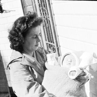 Woman holding a baby on a porch.