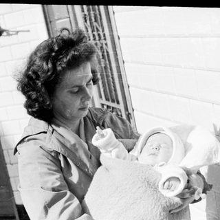 Woman holds a baby wrapped in a blanket.