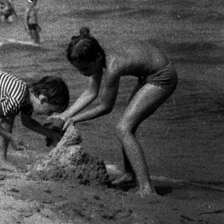 Children playing on a sandy beach near the ocean.