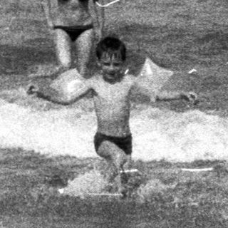 People wading in the ocean on a beach.