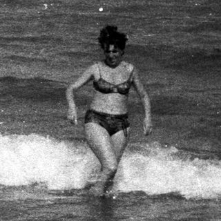 People wading in the ocean on a beach.