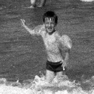 Boys playing in the ocean waves, monochrome photograph.