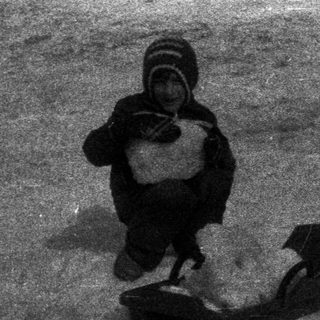 Child sledding down a snowy hill, vintage photograph.
