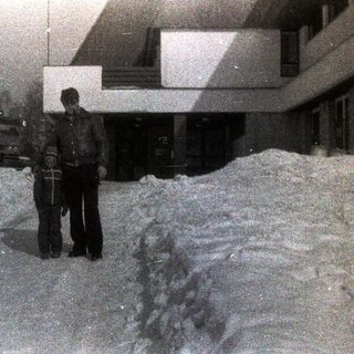 People stand in deep snow near a building.