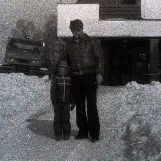 People stand in deep snow near a building.