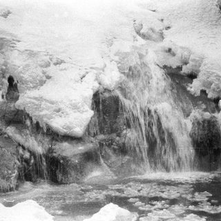 Icy waterfall with frozen formations and a dark pool.