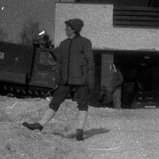Man walking past a building with snow piled high.