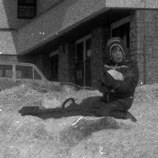 Man walking past a building with snow piled high.
