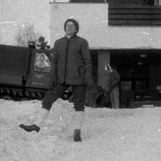 People stand near a building covered in heavy snowfall.