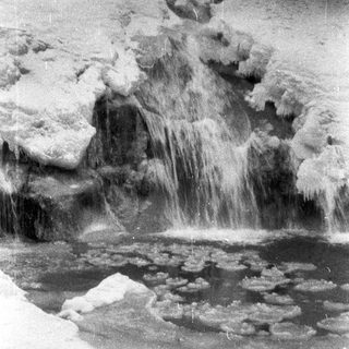Icy waterfall cascades over rocks in a frozen landscape.