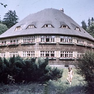 Round wooden house with windows, child in the foreground.