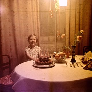 Girl seated at a table with a birthday cake.