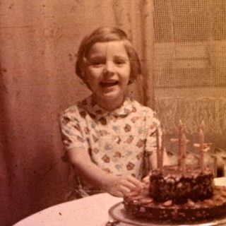 Girl seated at a table with a birthday cake.