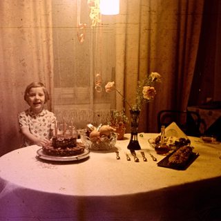 Girl seated at a table with a birthday cake.